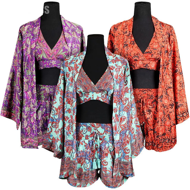 Three colorful bohemian kimonos on black mannequins - purple paisley kimono on left, turquoise and coral paisley kimono in center, and orange paisley kimono on right, all featuring flowing sleeves and intricate patterns